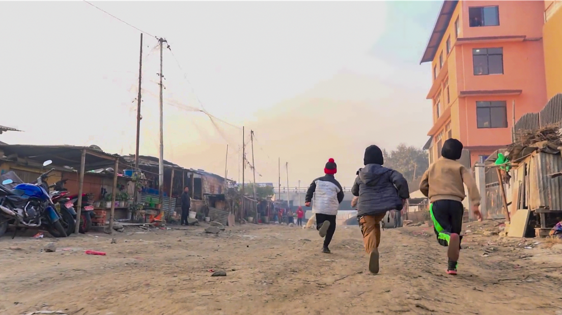 A photo of three children running through the streets of Kathmandu