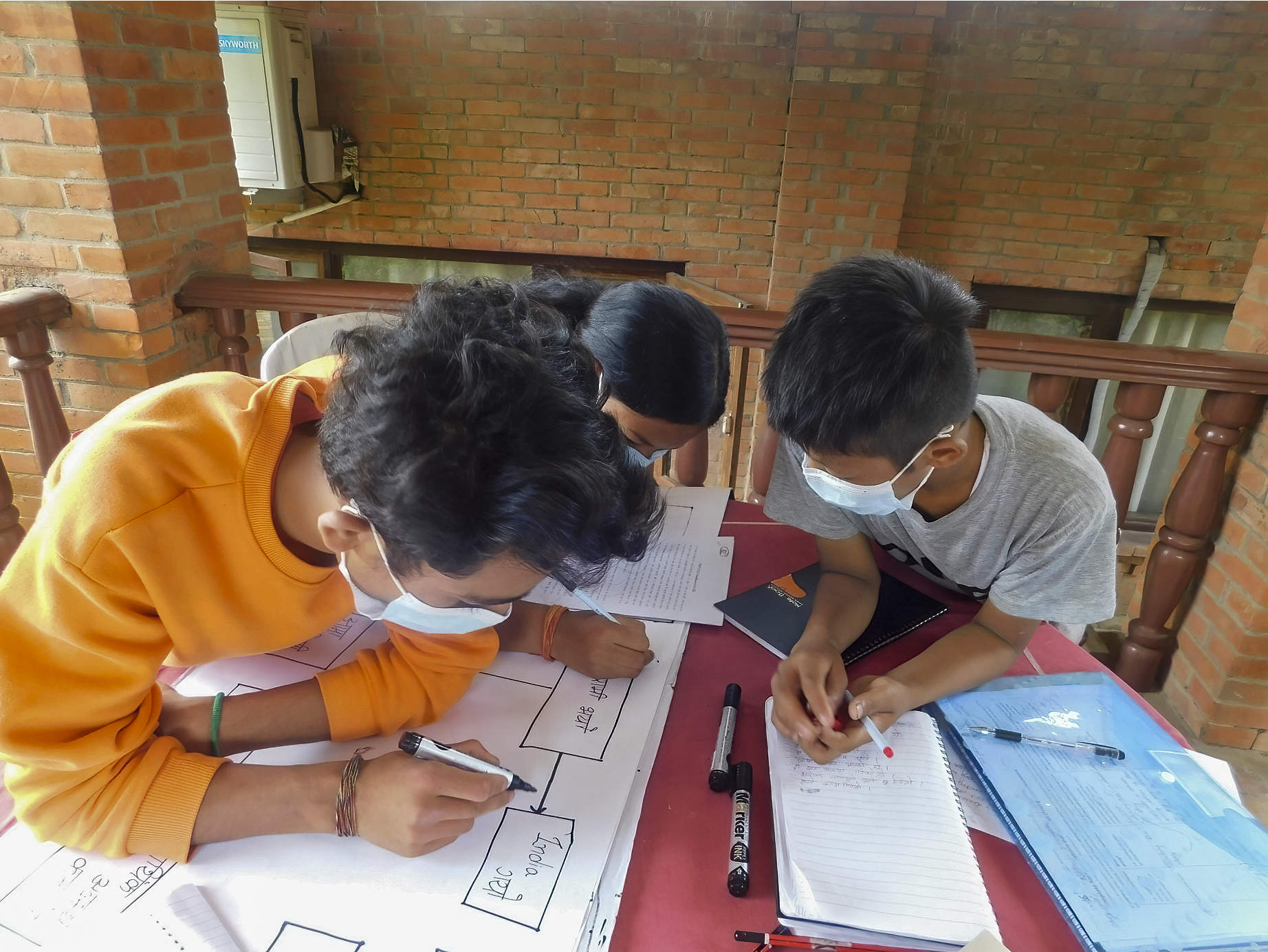 A photo of three children working together over a table