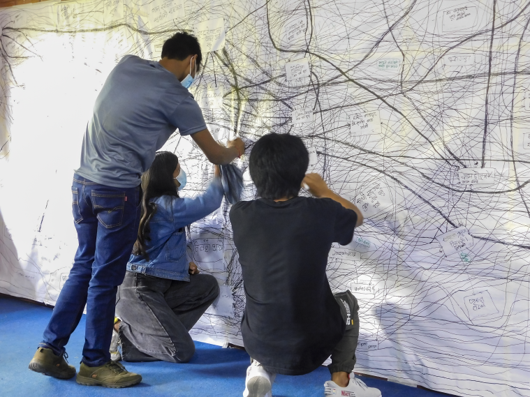 A photo of three people working together on a big system map