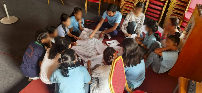 A photo of children sat on the floor, collaboratively writing on a large sheet of paper.