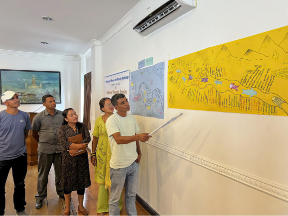 A photo of people looking at a Rivers of Life drawing on a wall. 