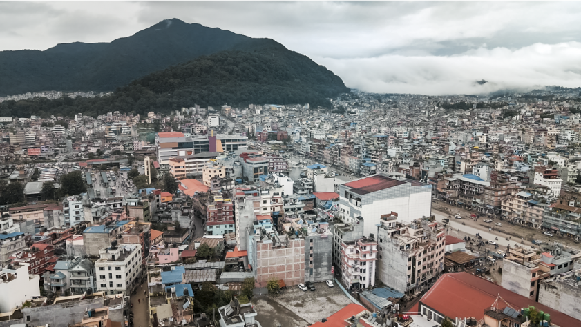 A landscape view of Kathmandu with mountains in the background and high rise buildings.