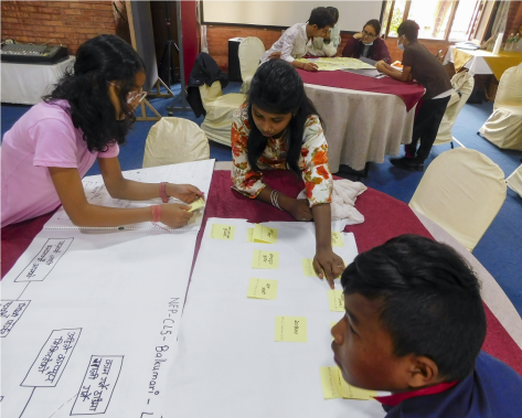 A photo of children working collaboratively at a table to map their experiences