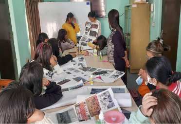 A photo of female children sat around a table looking at a number of printed photographs.