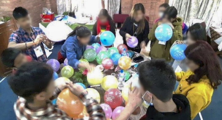 A photo of children surrounding a table filled with balloons.