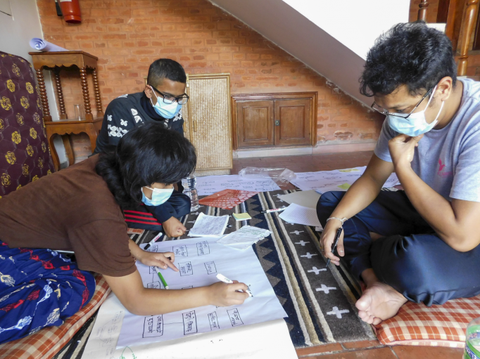 A photo of three people sat on the floor working collaboratively